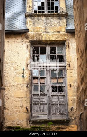 Old stone derelict house with broken windows and shutters Stock Photo