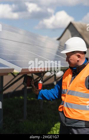 Engineer in a hard hat and reflective vest maintains solar panels Stock Photo