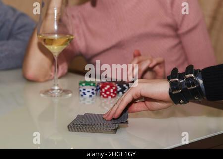 Women's hands shuffle cards. Concept of playing poker on the table with chips and cards. A glass of champagne. Gambling concept. Enjoying the moment, digital detox with friends. Selective focus. Stock Photo