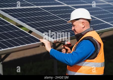 Solar power plant worker with electric wrench in his hands inspects panels Stock Photo