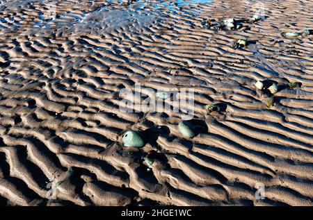 smooth stones breaking up the ripples in the sand beach made by the tides, Morecambe Bay, Lancashire, England Stock Photo