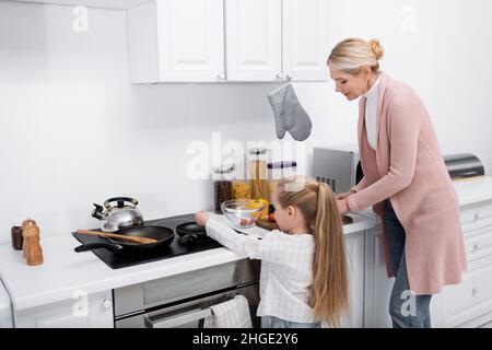 little girl helping grandmother cooking in kitchen Stock Photo
