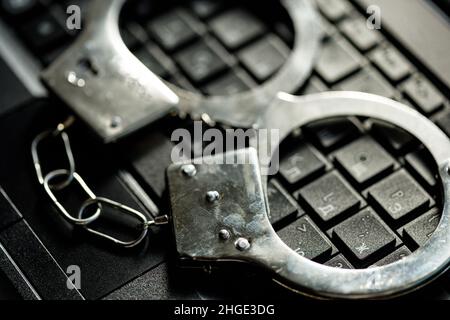 handcuffs on the laptop keyboard. hacker crimes. High quality photo Stock Photo