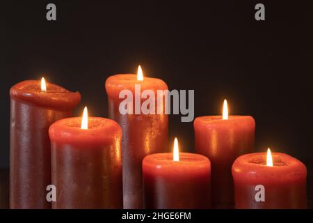 Red candles lit in a dark room with a black background with copy space Stock Photo