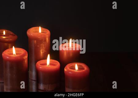 Red candles lit in a dark room with a black background with copy space Stock Photo