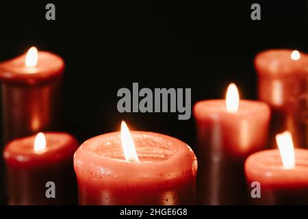 Red candles lit in a dark room with a black background with copy space Stock Photo