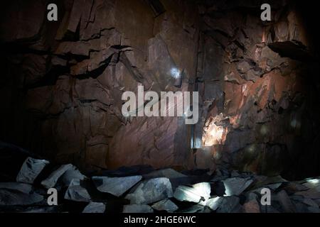 slate seam boundary rock illuminated by visitors head torches inside the honister slate mine lake district, cumbria, england, uk Stock Photo