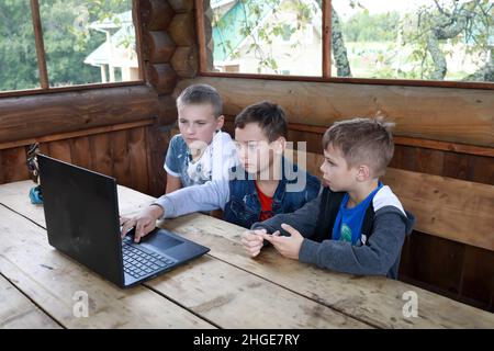 Three children using laptop in gazebo, Karelia Stock Photo
