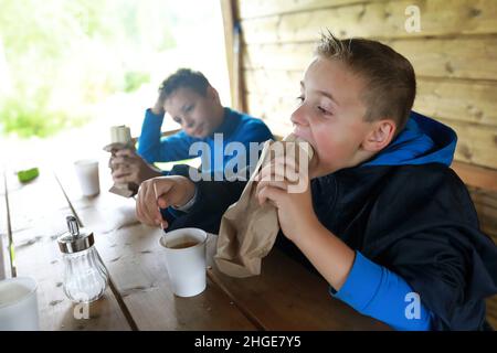 Children eating hot dogs on restaurant terrace Stock Photo