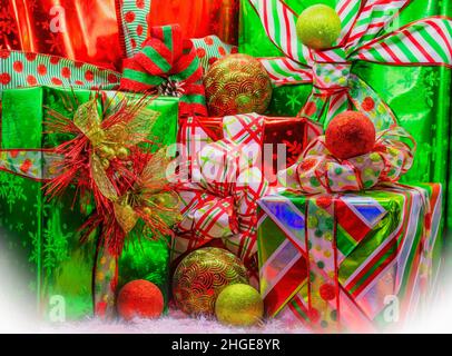 Christmas time still life with brightly wraped presents with fun bows and ornaments. Stock Photo