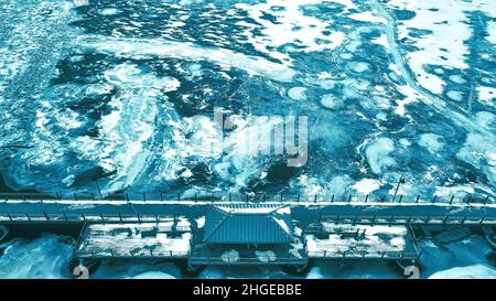 Elevated view of the trestle (friendship) trail in winter.The water is frozen over with snow. A blue black and white theme is over the image. Stock Photo