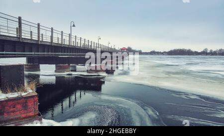 The frozen landscape with hiking/walking trail bridge over the frozen water. The trestle (friendship) trail extends to another city over the lake. Stock Photo