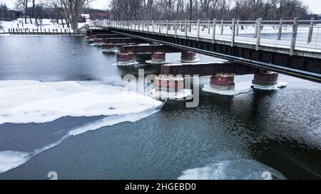 The frozen landscape with hiking/walking trail bridge over the frozen water. The trestle (friendship) trail extends to another city over the lake. Stock Photo