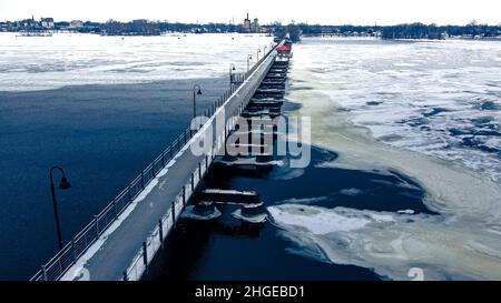 The frozen landscape with hiking/walking trail bridge over the frozen water. The trestle (friendship) trail extends to another city over the lake. Stock Photo