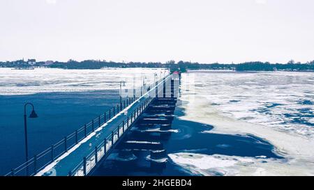 The frozen landscape with hiking/walking trail bridge over the frozen water. The trestle (friendship) trail extends to another city over the lake. Stock Photo