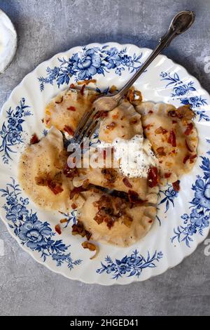 Traditional polish dumplings, pierogi, with fried onion and bacon Stock Photo
