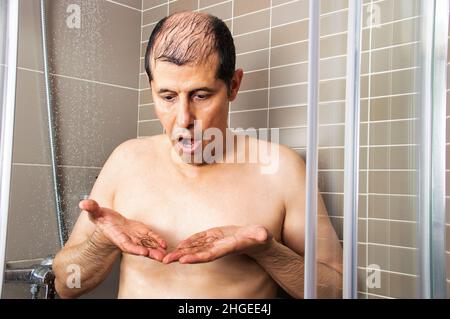 Man showering and checking that his hair falls out Stock Photo