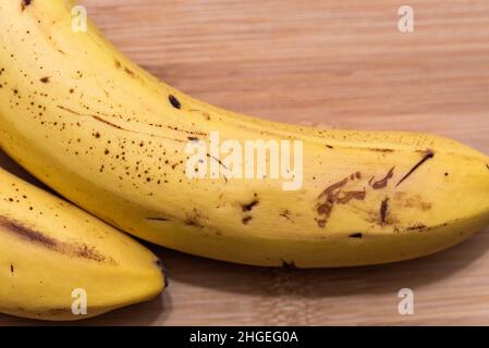 Ripe bananas with black spots. Close-up sweet yellow banana fruit on a bamboo board. Stock Photo