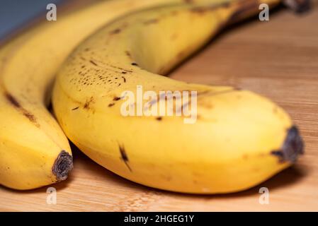 Ripe bananas with black spots. Close-up sweet yellow banana fruit on a bamboo board. Stock Photo