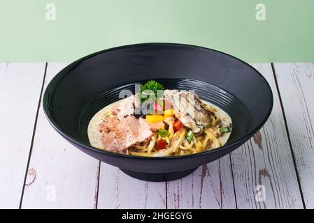 Italiano cuisine Pasta Truffle Cream in black bowl on wooden table Stock Photo