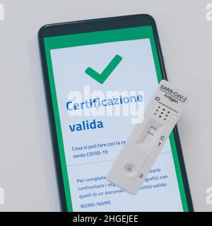 Closeup view of gloved hand with SARS-CoV-2 rapid antigen test nasal and phone with green digital certificate on display. Health, healthcare, corona v Stock Photo