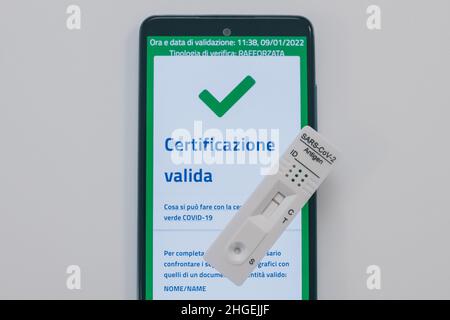 Closeup view of gloved hand with SARS-CoV-2 rapid antigen test nasal, phone with green digital certificate on display. Health, corona virus, pandemic Stock Photo