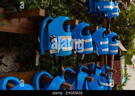 life jackets hanged on plain grey wall by swimming pool for emergency, filter effect Stock Photo