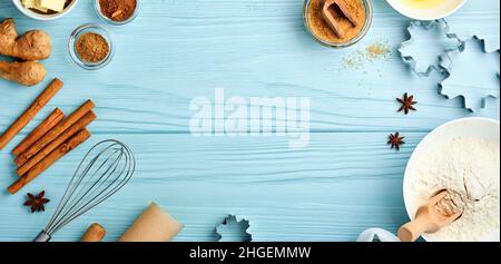 Baking background with ingredients for making gingerbread flour, eggs, kitchen tools, utensils and cookie molds on blue wooden table. Top view. Flat l Stock Photo