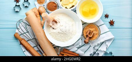 Baking background with ingredients for making gingerbread flour, eggs, kitchen tools, utensils and cookie molds on blue wooden table. Top view. Flat l Stock Photo