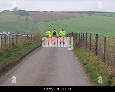 A group of workmen walk along Maiden Castle Road, Dorchester, Dorset in the direction of Maiden Castle. Stock Photo