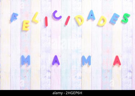 Photograph of some magnet letters with the Spanish text Congratulations Mom on a colored cardboard background.The photograph is shot in horizontal for Stock Photo