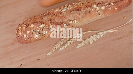 Different types of bread, fresh pastries in the bakery. Bread with sesame seeds, cereals, seeds. Different forms and types of rolls. Wheat ears on a w Stock Photo