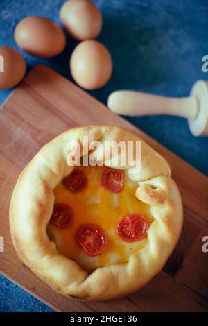 Deep Dish Pizza. Сhicago pizza 4 cheeses, dried cherry tomatoes. Food on a wooden plate, rolling pin and 4 eggs, recipe pie pizza. Festive pastry on a Stock Photo