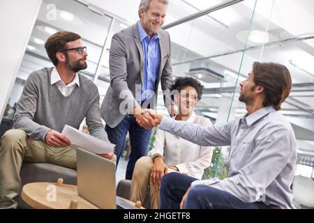 You've done well. Shot of a two business professionals shaking hands in an office. Stock Photo
