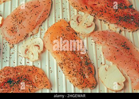 Photo of salmon. Fresh red fish rich color. Mushrooms and chicken fillet on the grill. in spices, dried basil, salt, pepper. Salmon inon the electric Stock Photo