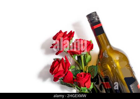 Valentine's Day background. Wine bottle with bouquet of red plastic roses on isolated white backgrounds. Top view, copy space Stock Photo