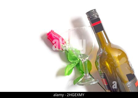 Valentine's Day background. Wine bottle with red rose and empty glass on isolated white background. Stock Photo