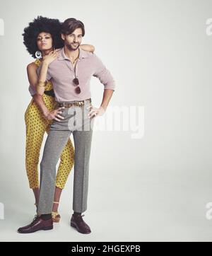 The perfect retro couple. An attractive young couple standing together in retro 70s clothing. Stock Photo
