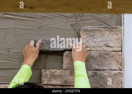 Professional worker gluing decorative brick on mounting wall Stock Photo