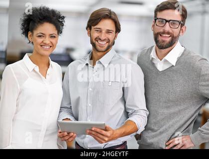 Young, successful and positive. Portrait of three young businesspeople standing in his office. Stock Photo