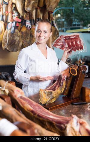 Positive young woman holding iberian ham Stock Photo