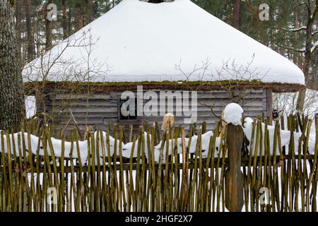 Old wooden log house covered with snow in a winter forest. Stock Photo