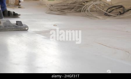 Workers in uniform cleaning room with a vacuum cleaner after installing wood parquet board during flooring work. Man vacuuming floor during repairs. Stock Photo