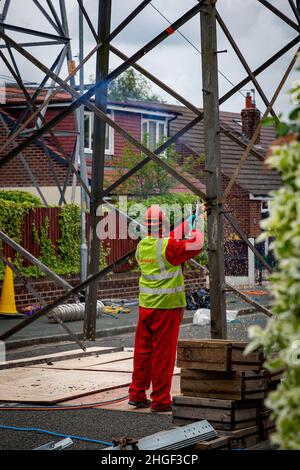 Workmen in PPE use oxy acetylene torches to cut out damaged parts of a grounded electricity pylon Stock Photo