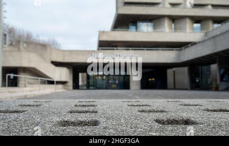 National Theatre on South Bank of the River Thames. The complex designed by Denys Lasdun was built in brutalist style. Concrete bench in foreground. Stock Photo