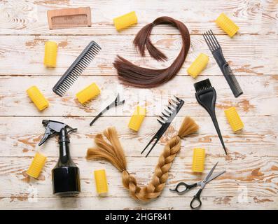 Hairdresser's tools with curlers and strands on light wooden background Stock Photo
