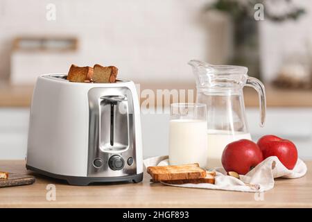 White toaster with apples and glass of milk on table in modern kitchen Stock Photo