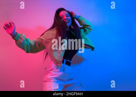 The brunette dances in neon, the dancer in red-blue. Hip hop girl, party, smile. Stock Photo