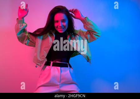 The brunette dances in neon, the dancer in red-blue. Hip hop girl, party, smile. Stock Photo