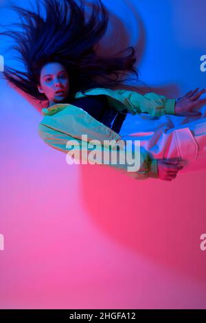 The brunette dances in neon, the dancer in red-blue. Hip hop girl, party, smile. Stock Photo